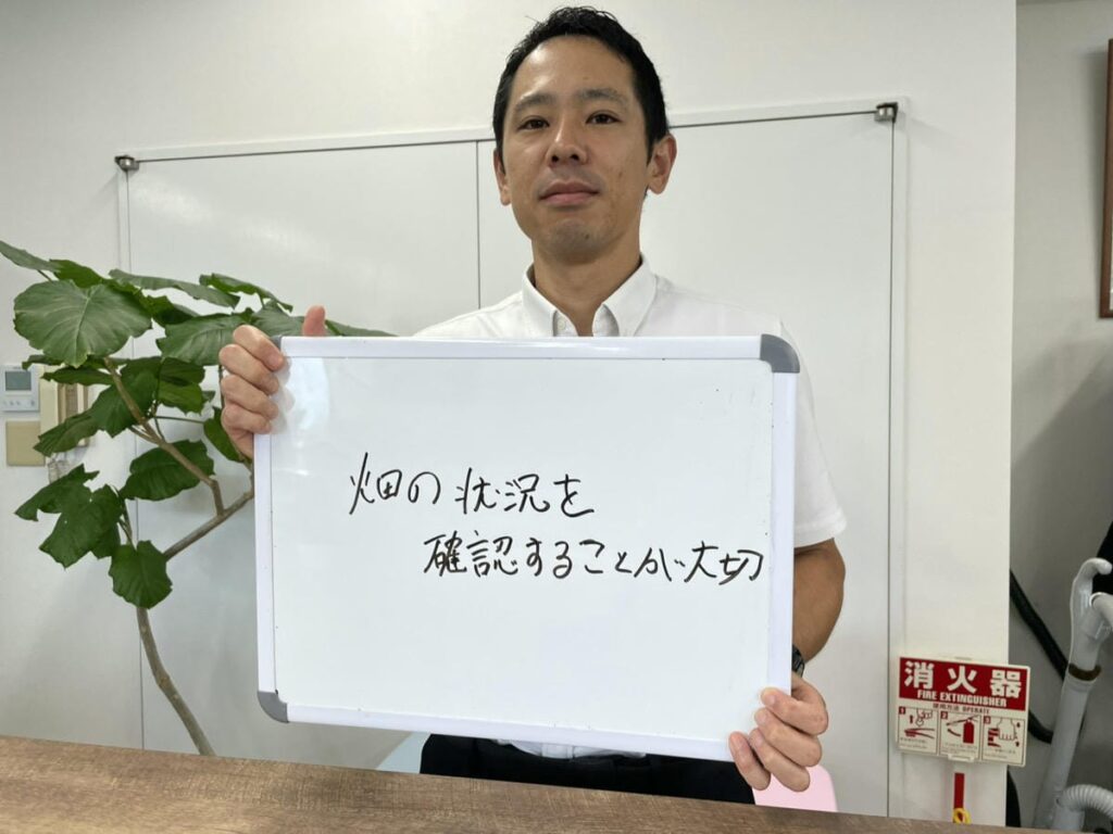 ビニールハウスの解体について解説し、ホワイトボードを持つ初田理事