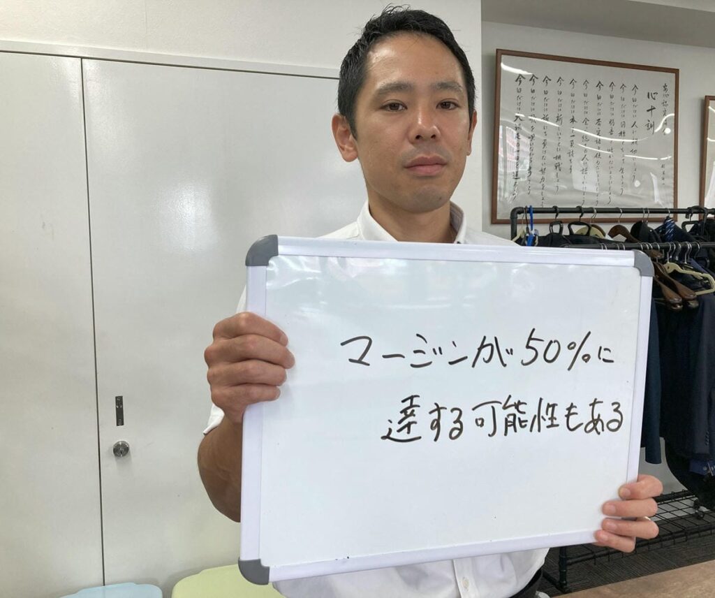 中間マージンについて解説するホワイトボードを持つ初田さん